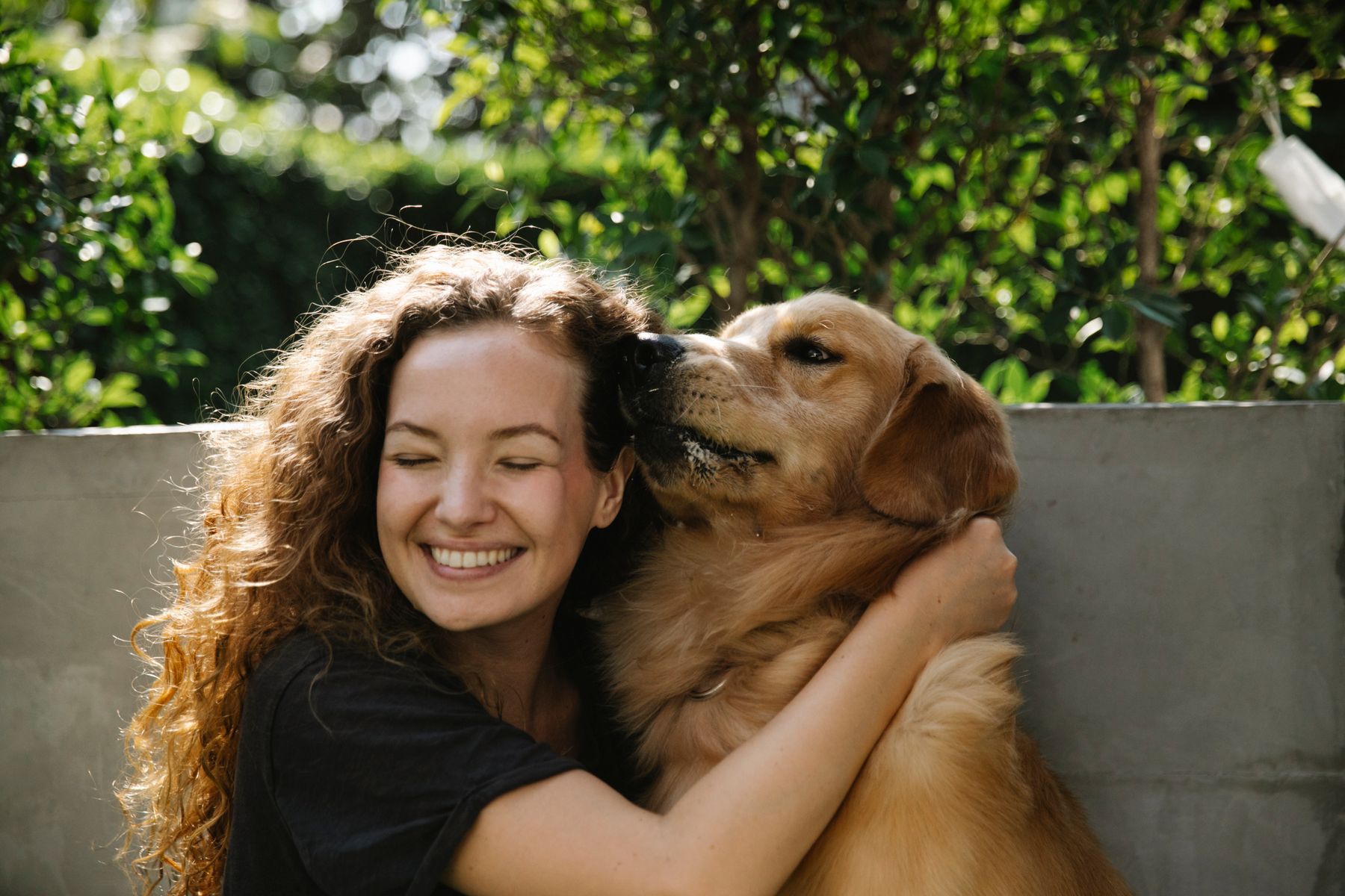 A woman with her golden retriever in a sunlit garden